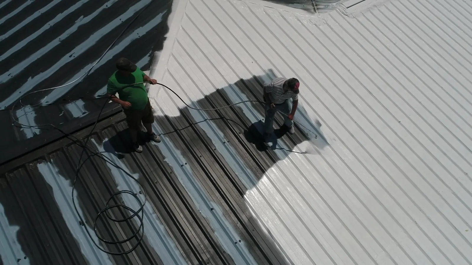 Crew applying a color coating to a commercial metal roof